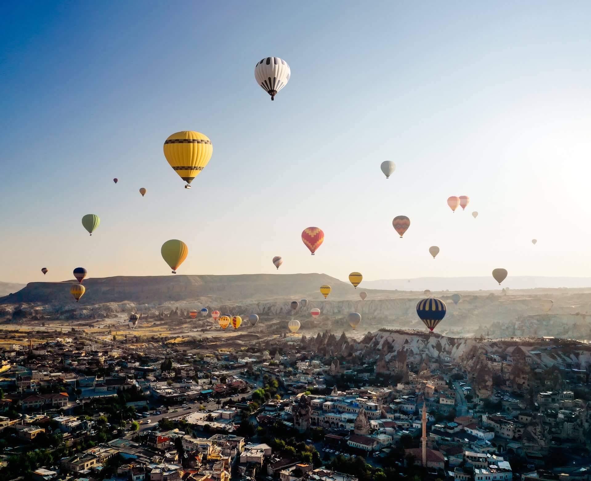 Colorful hot air balloons float above a town, symbolizing how debt relief works—lifting burdens and elevating spirits against rocky formations and mountains.