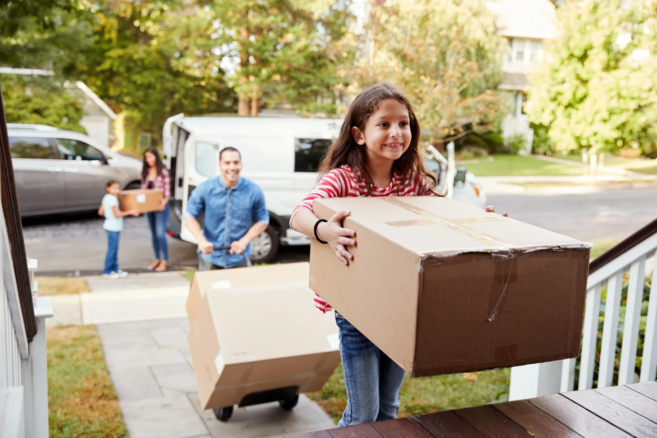 A family joyfully carrying boxes, celebrating their journey of buying a home for the first time.